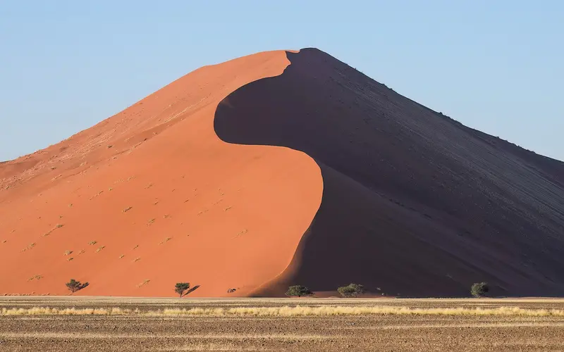 Dune 45 at sunrise in Sossusvlei, with one side lit orange and the other in shadow
