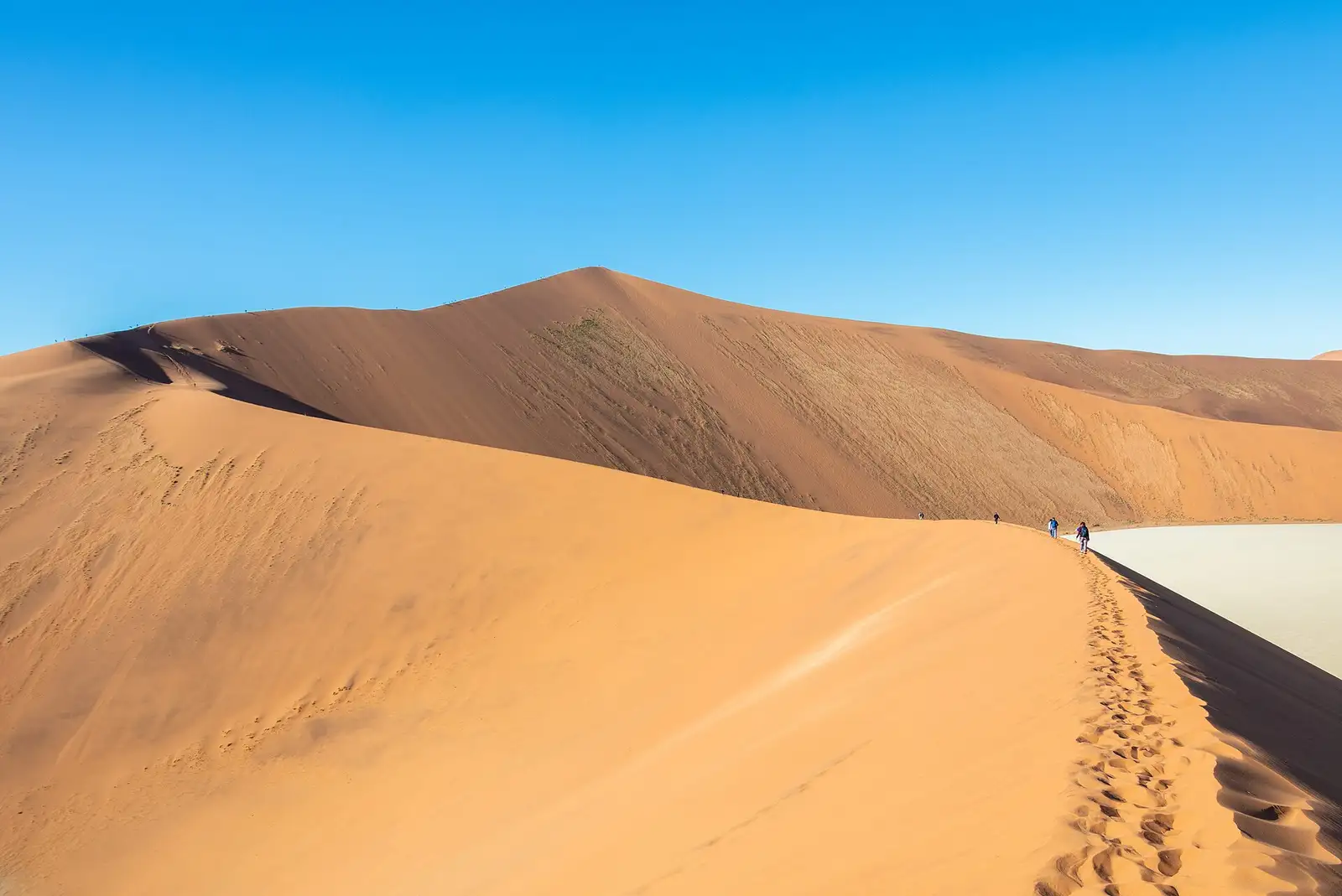 Hikers walking along a dune ridge in Sossusvlei