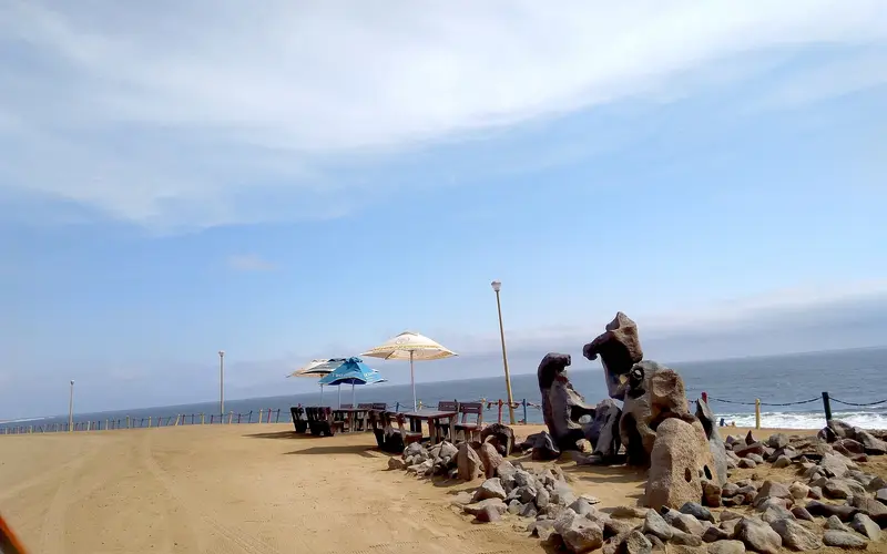 Seafront viewpoint with picnic tables, umbrellas and rock sculptures above the beach in Henties Bay