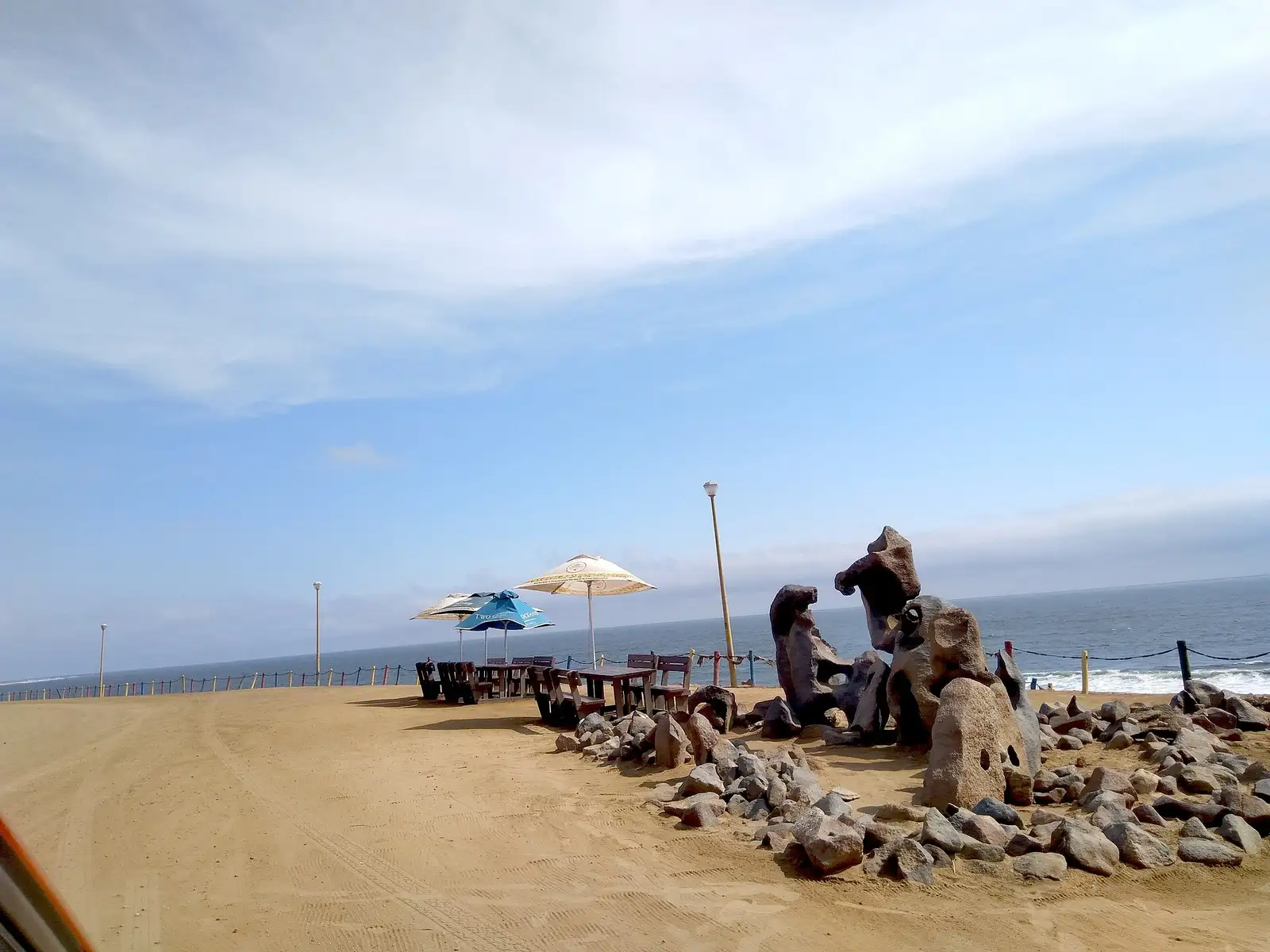 Seafront viewpoint with picnic tables, umbrellas and rock sculptures above the beach in Henties Bay