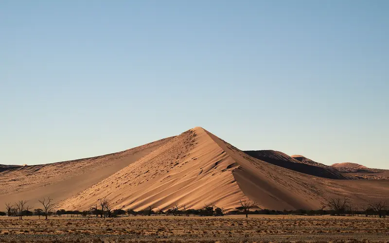 A red dune rising beside the road through the Namib Desert towards Sossusvlei