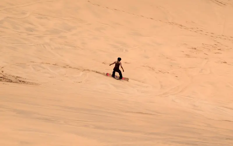 Lone sandboarder standing on top of a big dune near Swakopmund