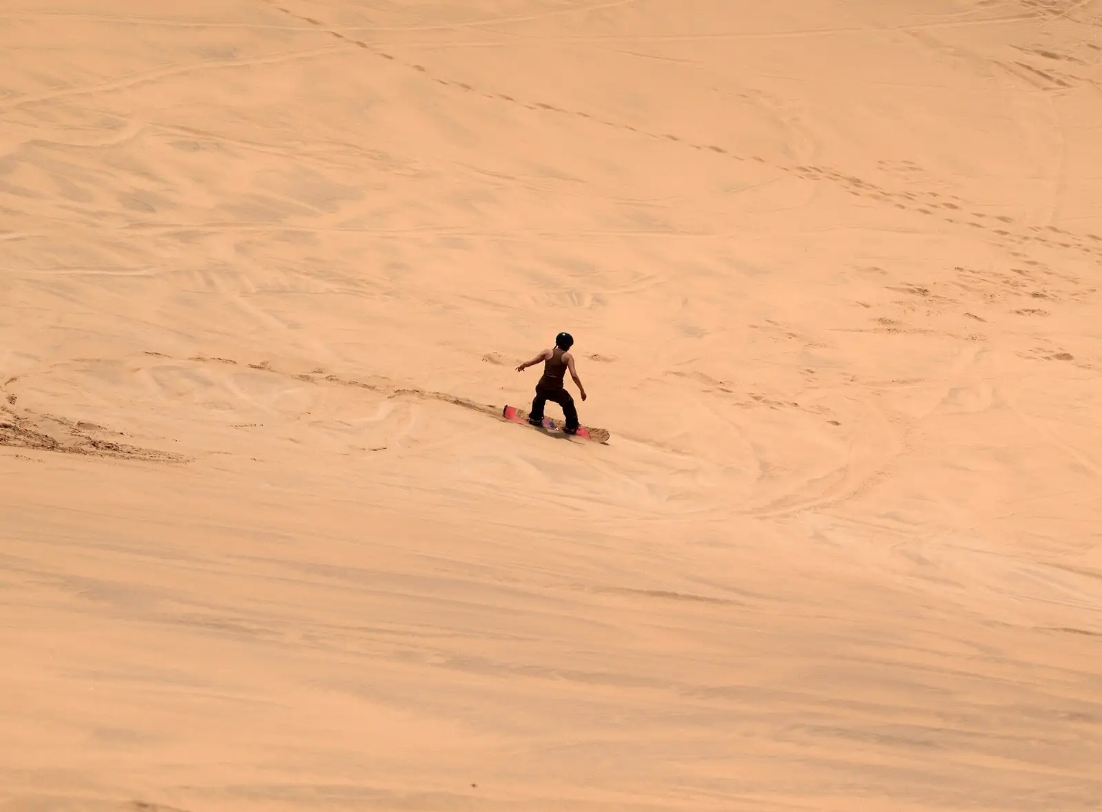 Lone sandboarder standing on top of a big dune near Swakopmund
