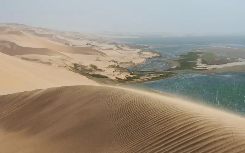 Huge sand dunes meeting the lagoon and the Atlantic at Sandwich Harbour, Namibia