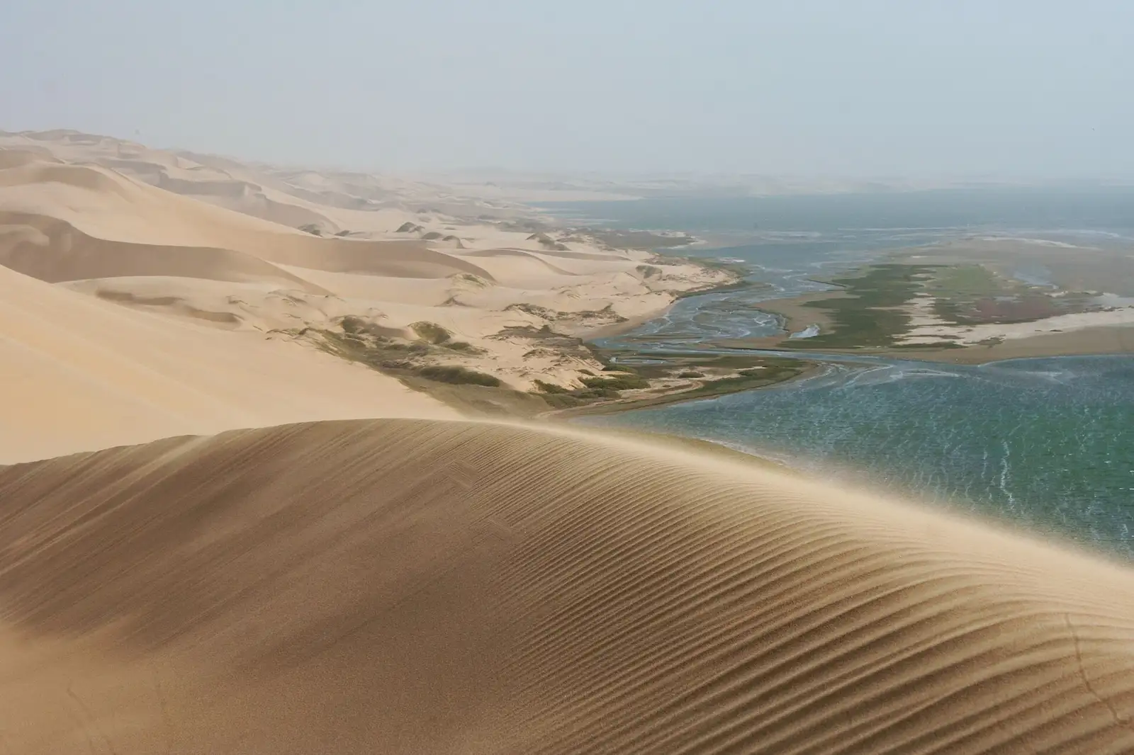 Huge sand dunes meeting the lagoon and the Atlantic at Sandwich Harbour, Namibia