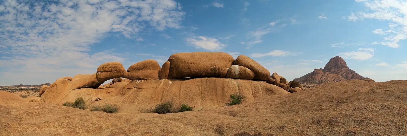 Granite boulders and the rock arch at Spitzkoppe under a blue sky