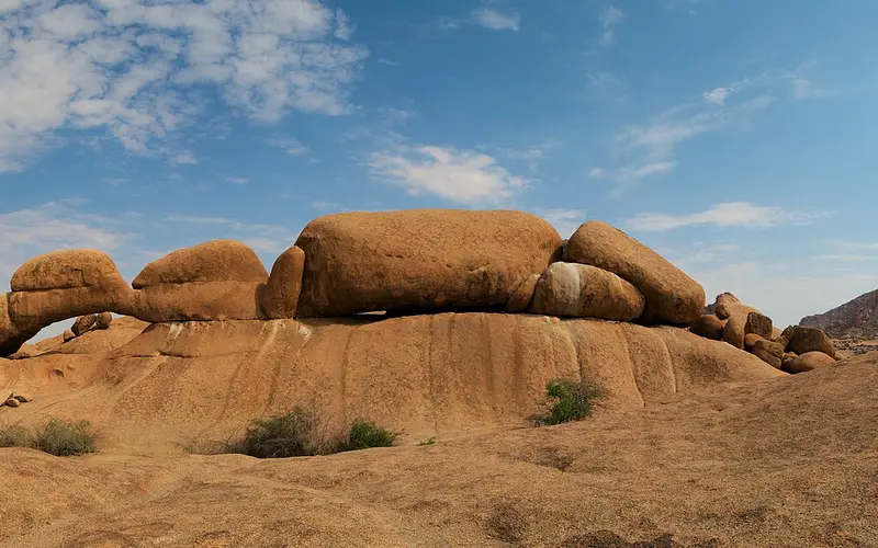 Granite boulders and the rock arch at Spitzkoppe under a blue sky